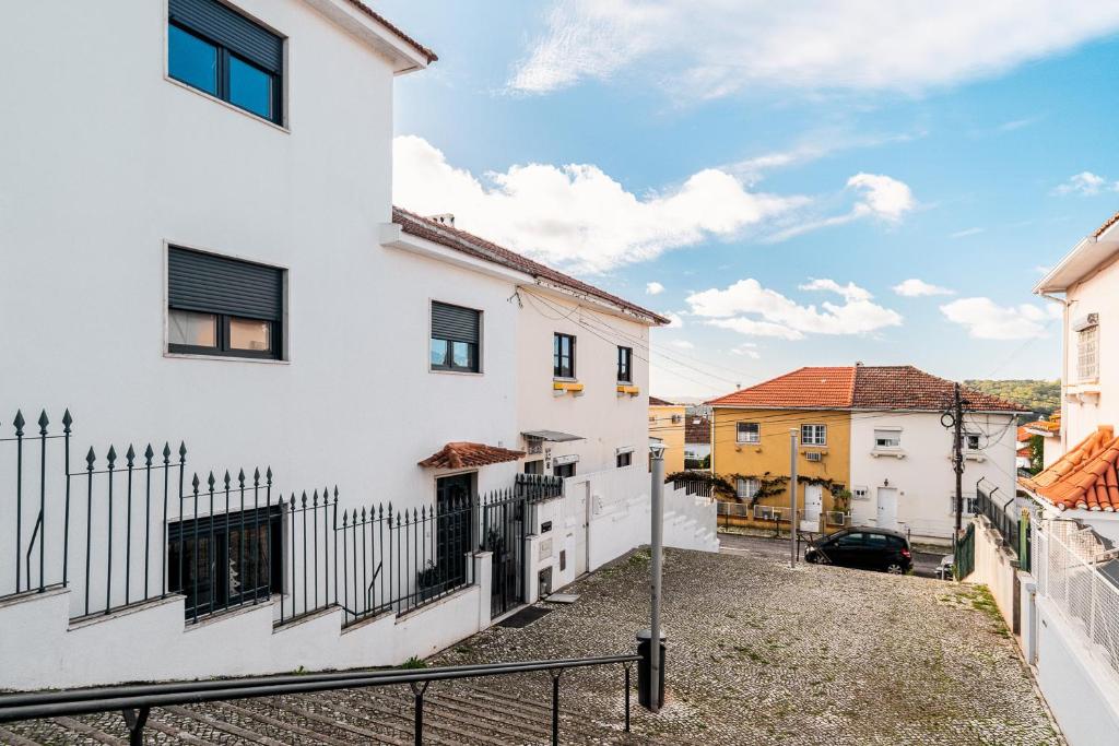 een uitzicht op de straat van een wit gebouw met een hek bij Aquedarte in Lissabon