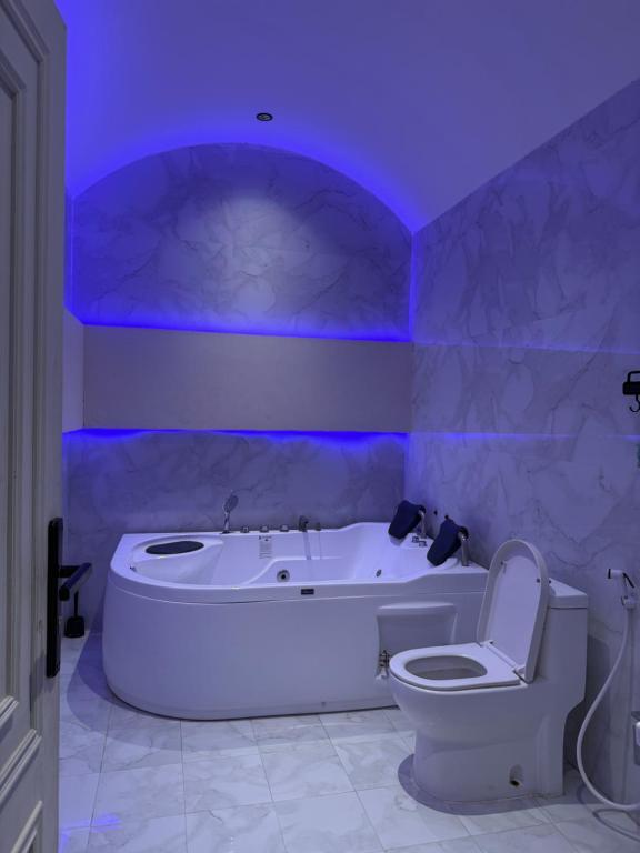 baño con bañera y aseo con luz púrpura en رويال دايموند, en Al-Hasa