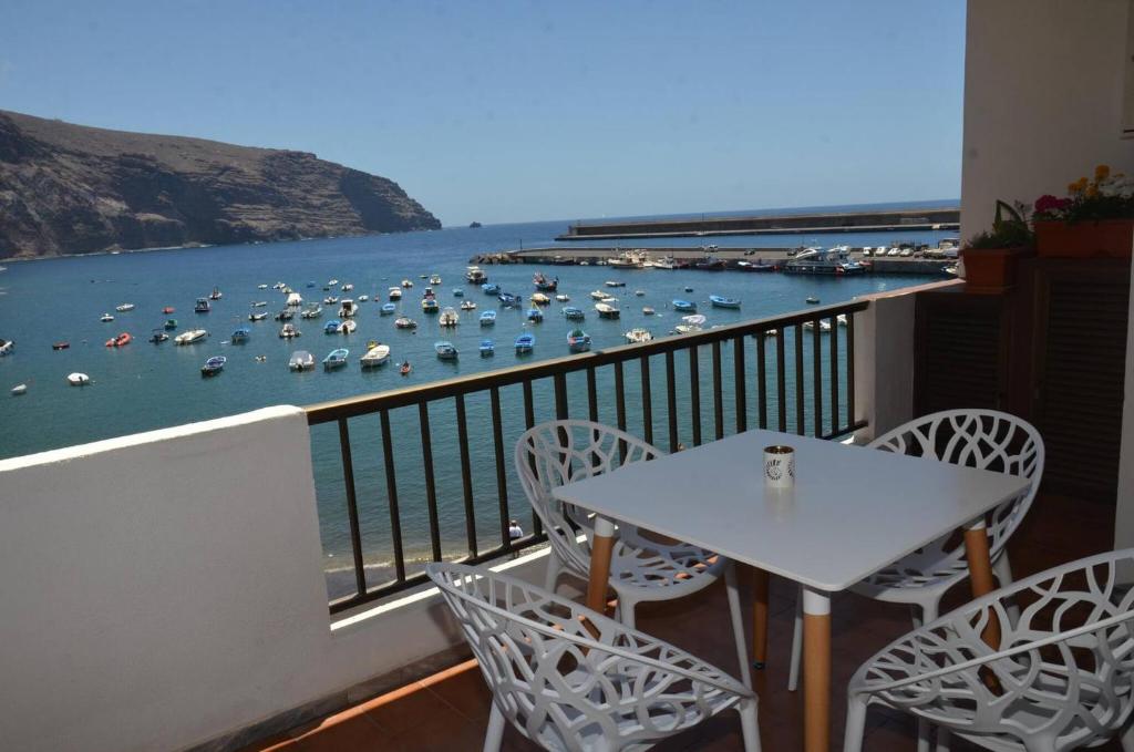 un balcone con tavolo, sedie e barche in acqua di Apt. Stella Playa a Valle Gran Rey