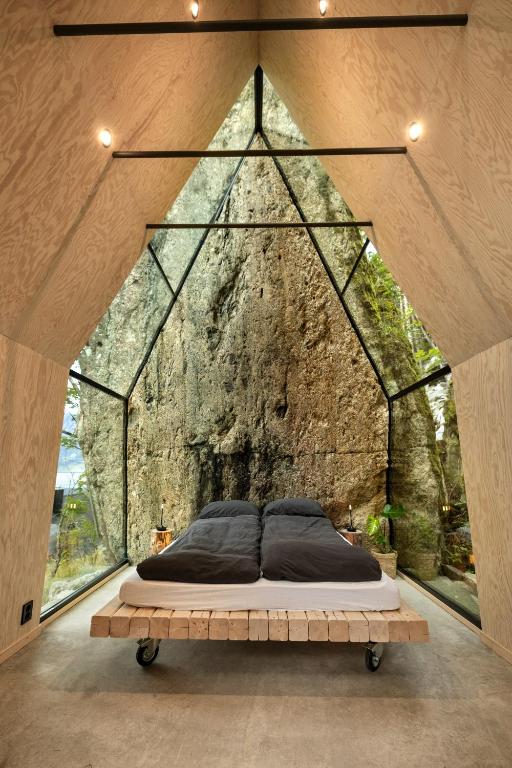 a bedroom with a bed in a glass house at Spectacular Fjord getaway - The Forge in Leirgulen