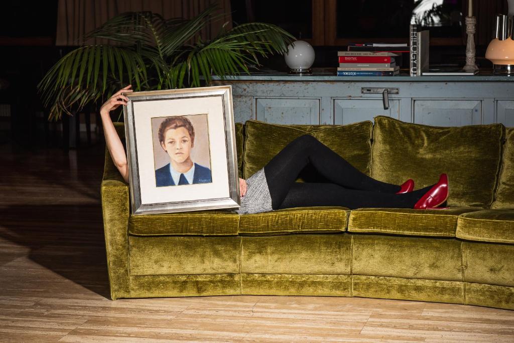 Eine Frau liegt auf einer Couch mit einem Bild in der Unterkunft Frida am Wald in Rasùn di Sotto