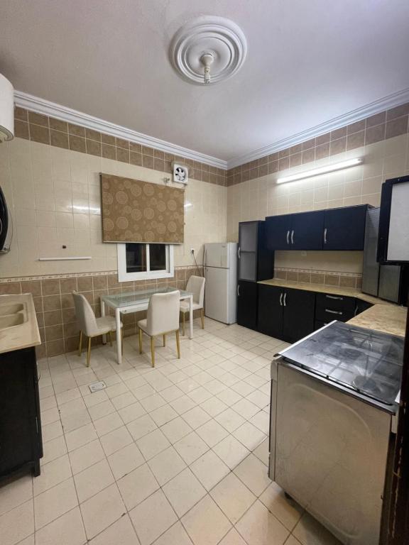a large kitchen with a table and chairs in it at شقة ثلاثة غرف نوم وصالة in Al Baha