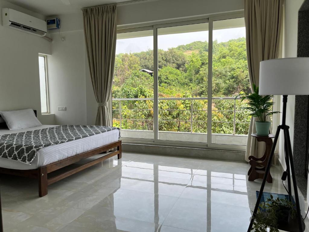 a bedroom with a bed and a large window at The Ashvem Horizon in Mandrem