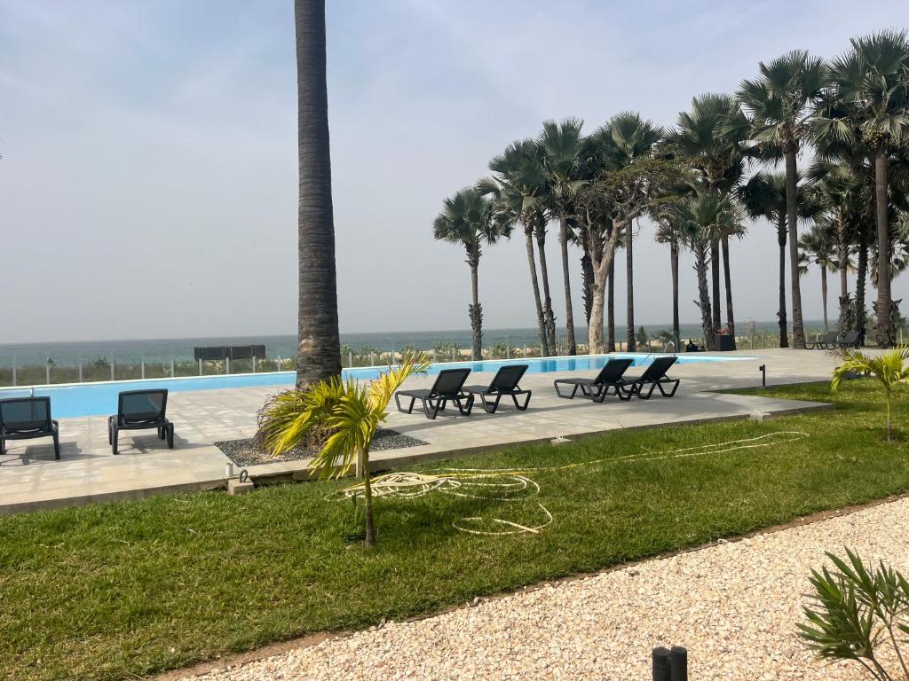 a row of chairs sitting next to a swimming pool at Gem Waterfront Butterfly Appartement in Bijilo