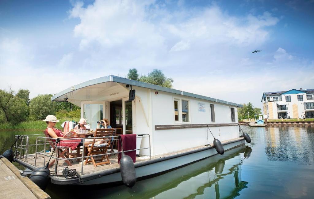 a house boat with people sitting on it on the water at Floating Apartments at Rechlin Harbor by Kuhnle-Tours in Rechlin