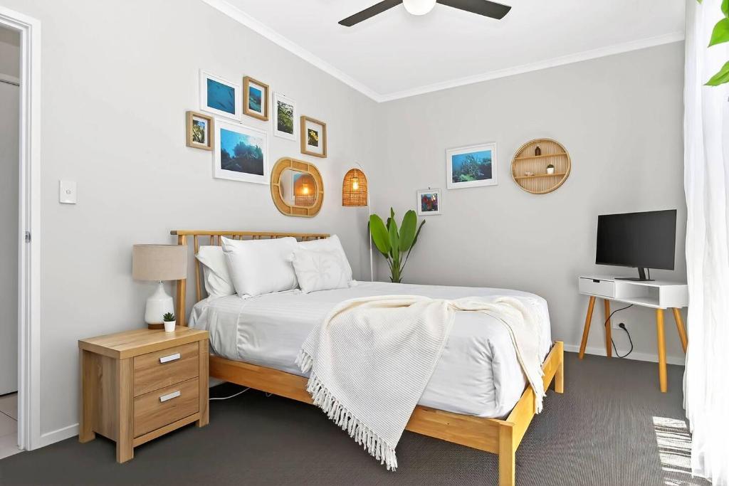 a white bedroom with a bed and a television at Reef Retreat - Modern Beach House Sanctuary in Port Noarlunga