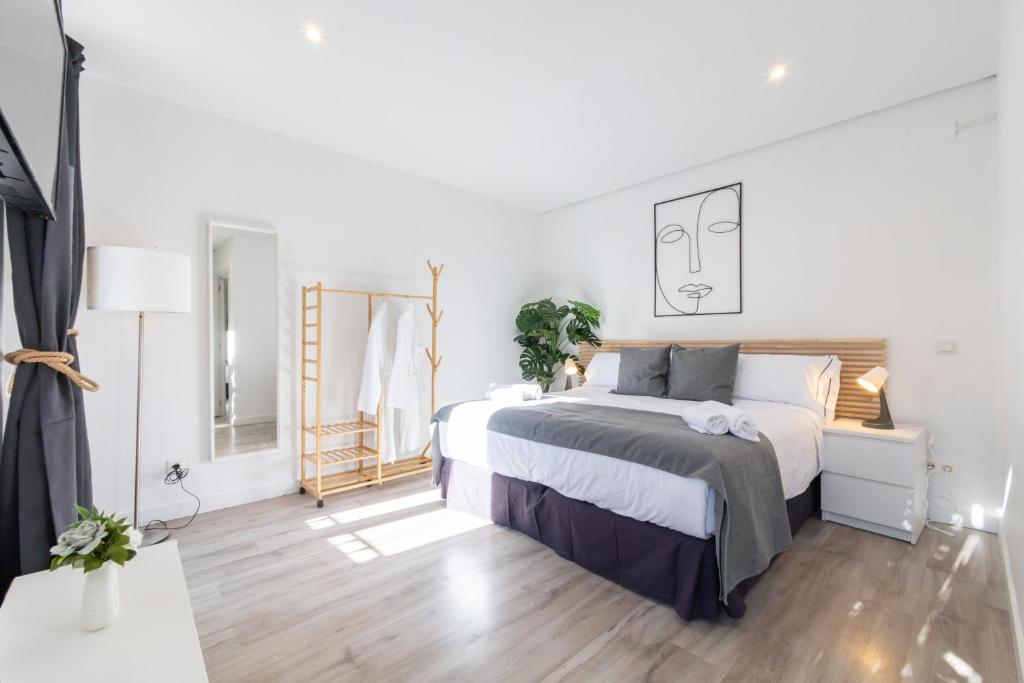 ein weißes Schlafzimmer mit großem Bett und Holzböden in der Unterkunft Amati Boutique Coliving Madrid in Madrid