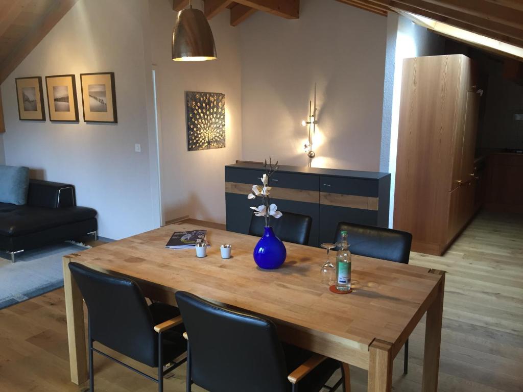 a wooden table with chairs and a blue vase on it at Ferienapartment Weitsicht in Biel