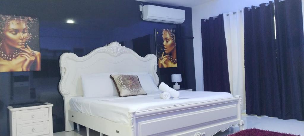 アンヘレスにあるJack Kandi Grosvenor Squareの白いベッドと壁に絵画が飾られたベッドルーム1室