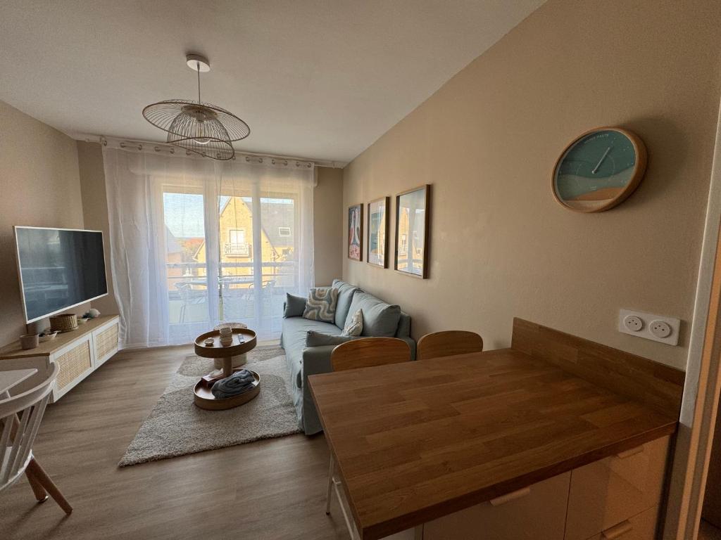 a living room with a couch and a table at La parenthèse bleue, loggia et parking in Courseulles-sur-Mer