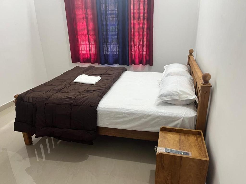 a bedroom with a bed with a wooden frame and red curtains at Mulberry homestay Munnar in Anaviratty