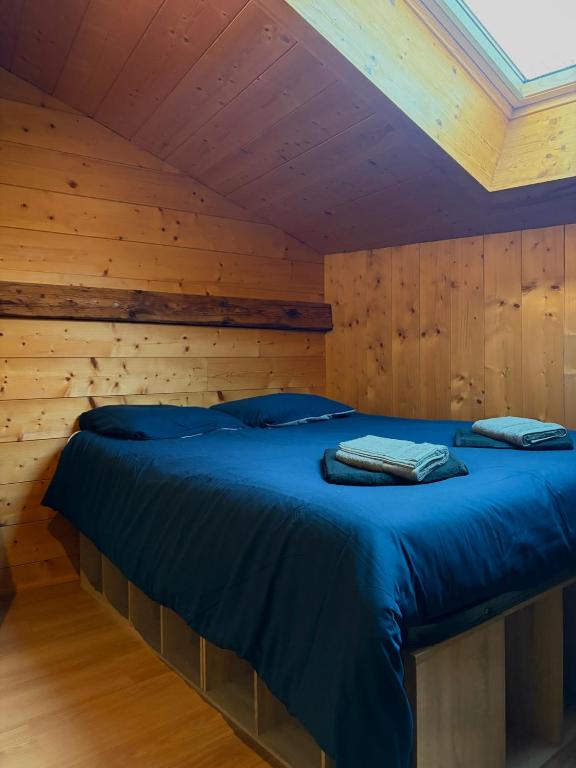 ein Bett in einem Zimmer mit einer Holzwand in der Unterkunft La Ruche, Maison chaleureuse de 5 personnes in Aigueblanche