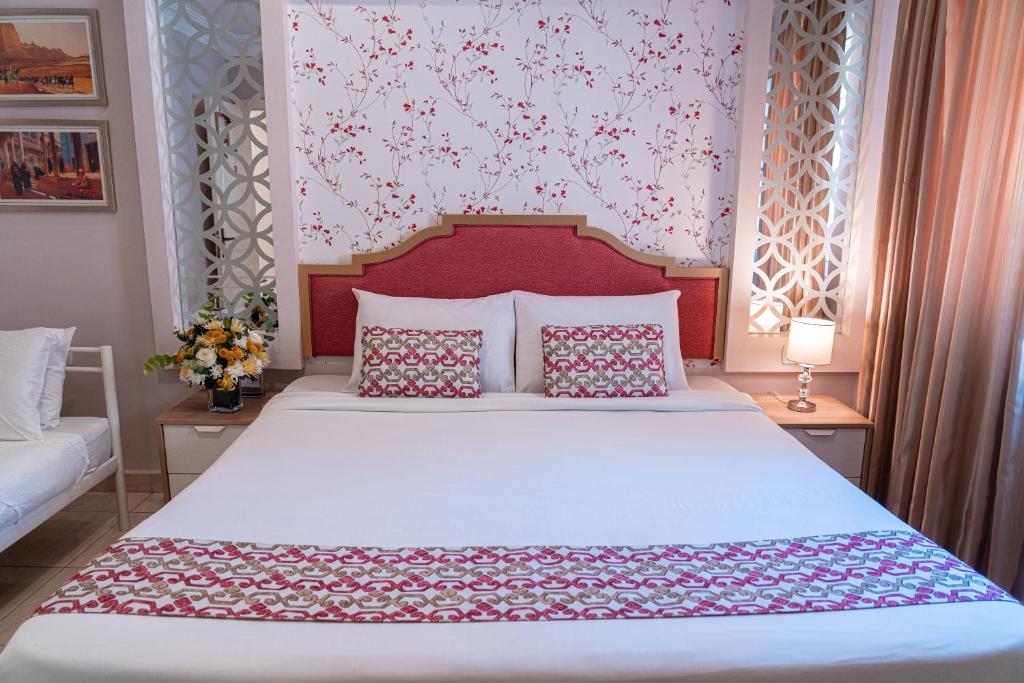 a bedroom with a white bed with a red headboard at Gallery Hotel in Amman