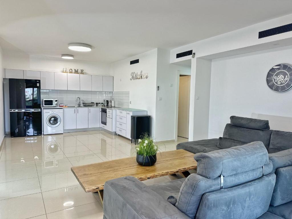 Una sala de estar con sofás y una mesa y una cocina. en דירות נופש רויאל פארק מביאים את הבית לחופשה, en Eilat