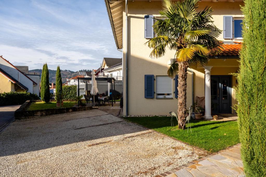 een huis met een palmboom naast een oprit bij Casa Mia by K A M E L U in Gengenbach