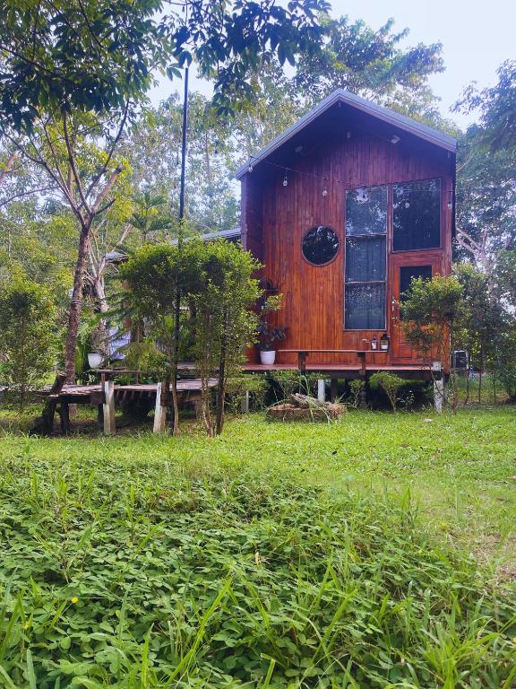 a small wooden house in a field of grass at Baanraipoonwana Baanboonmak in Ban Don Klang