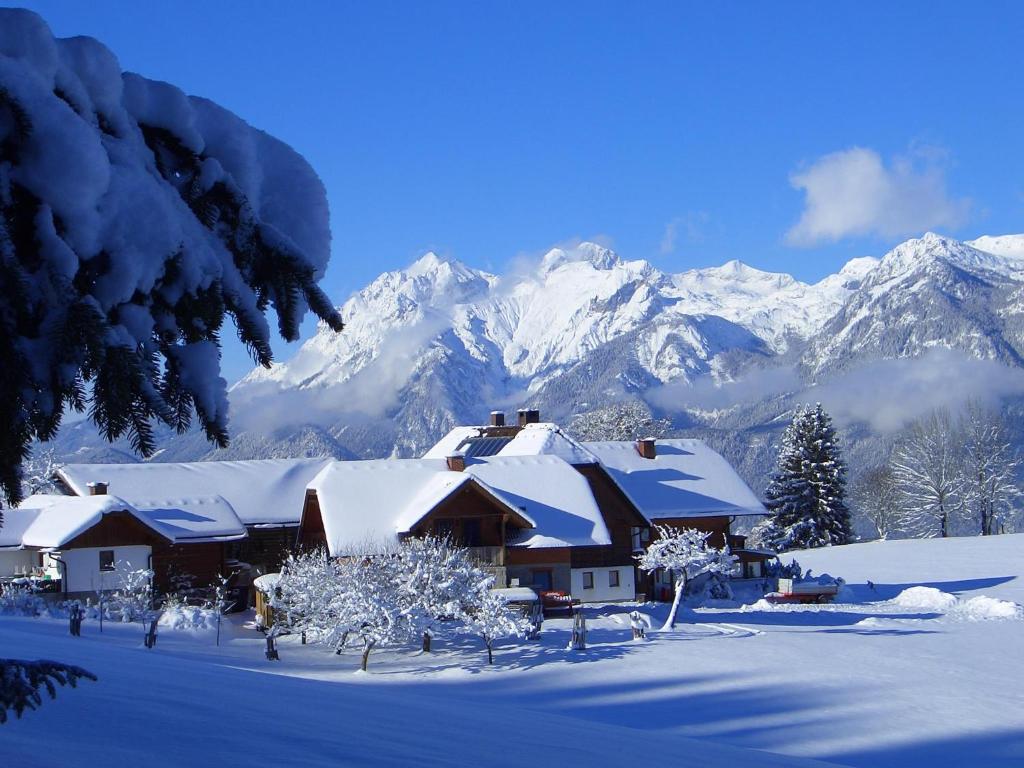 a house covered in snow with mountains in the background at Hirzhof SO Bike&Ski Ridehaus Ski In Ski Out in Auberg