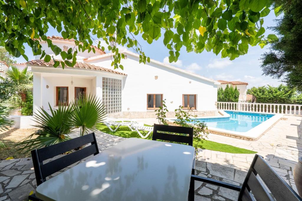 Una mesa y sillas frente a una casa con piscina. en Hauzify I Vanessa Park, en El Casalot