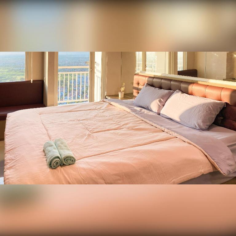 a bedroom with a large bed with a large window at Tanglin Tower with Netfix by AquHome in Surabaya