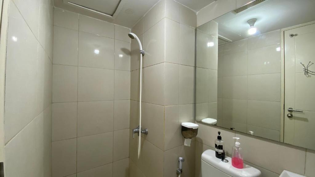 a white bathroom with a shower and a sink at Tanglin Tower with Netfix by AquHome in Surabaya