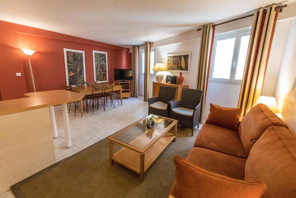 a living room with a couch and a table at Cannes Croisette Prestige Apart'hotel in Cannes