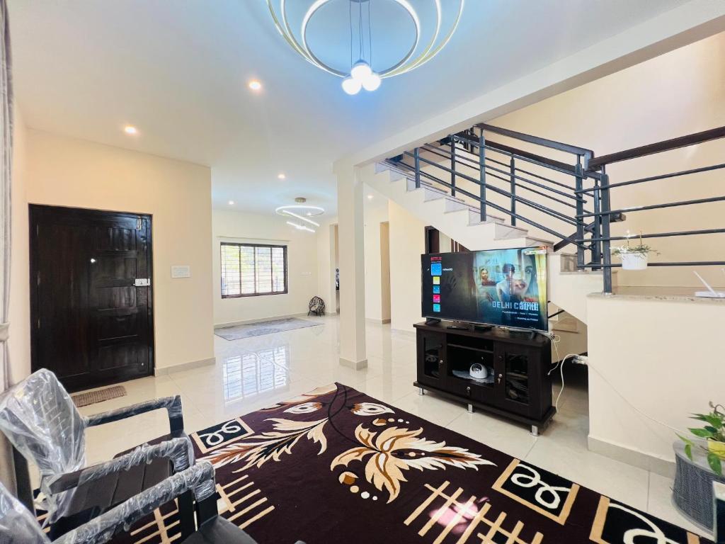 sala de estar con TV y escalera en Green Heaven Mysore Homestay, en Mysore