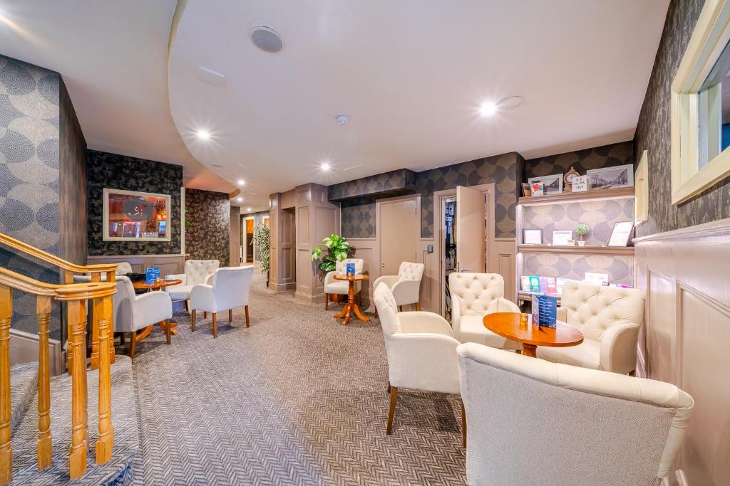 a waiting room with white chairs and tables at The Gateway Hotel in Swinford