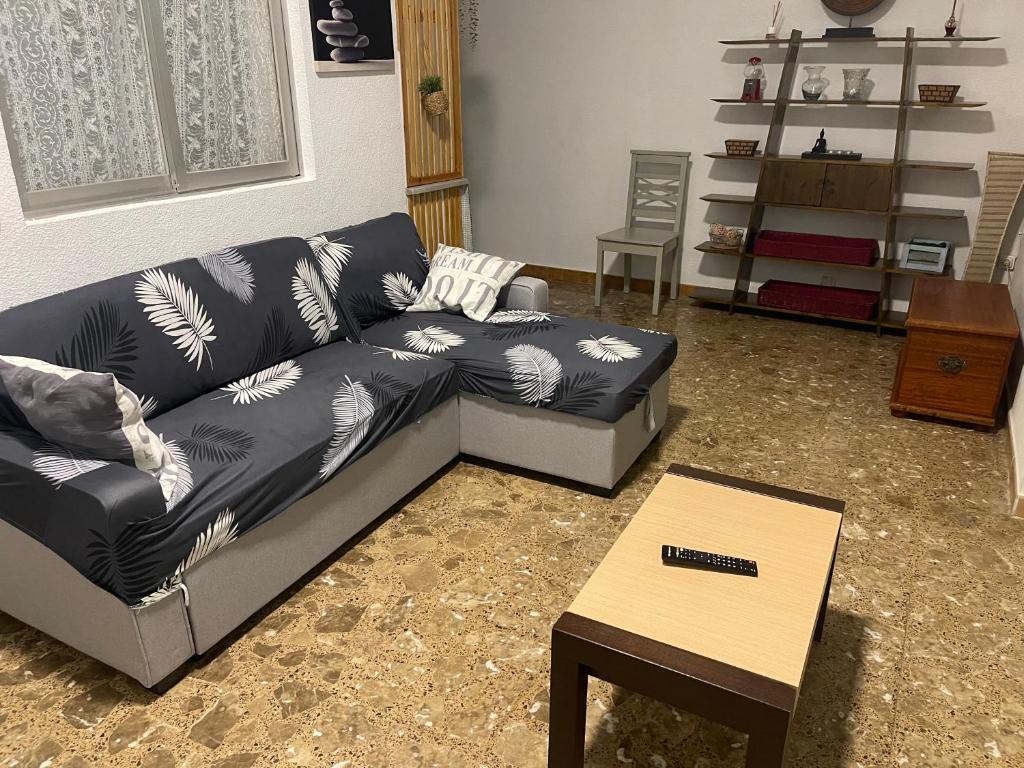 una sala de estar con un sofá y una mesa en Acogedora planta baja, en Benaguacil