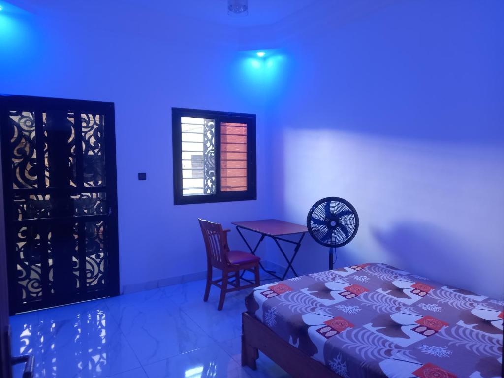 a bedroom with a bed and a table with a chair at Femi in Dakar