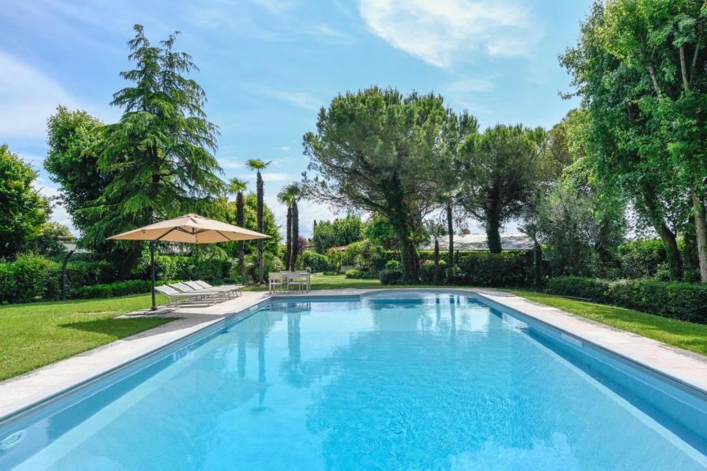 a swimming pool in a yard with an umbrella at Villa Maria by Garda FeWo in Moniga