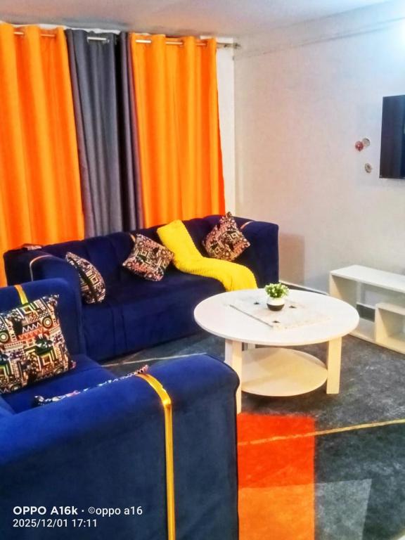 a living room with a blue couch and a table at Shalom Stays in Machakos