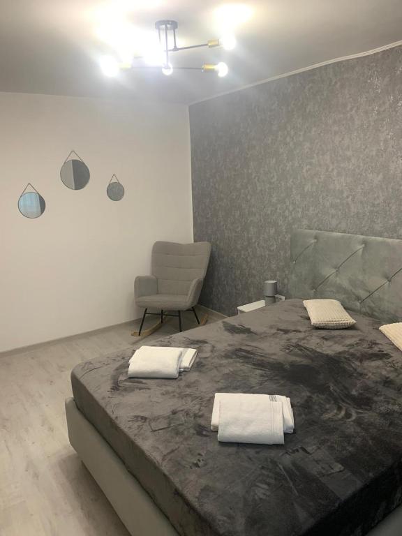 a bedroom with a large bed and a chair at Bia's apartament in Râşnov