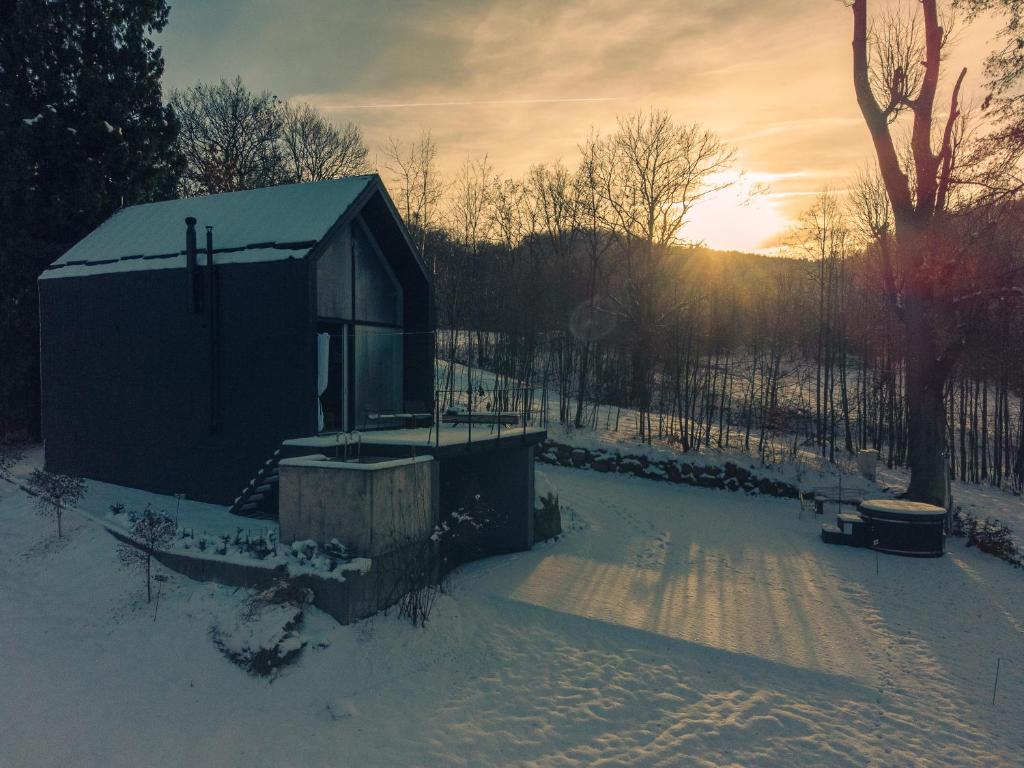 a small shed in the snow with the sunset in the background at Rest Hill -Domek z balią i sauną - Everslow in Sosnówka