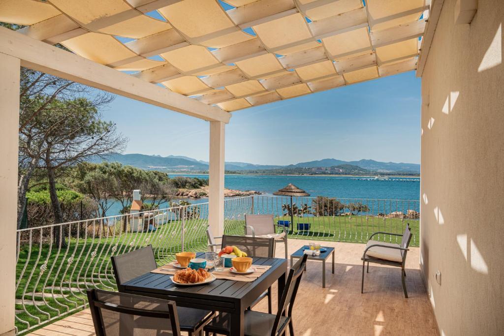 Una mesa y sillas en un patio con vista al agua. en Casa vacanza Cala Saccaia, en Isola della Bocca