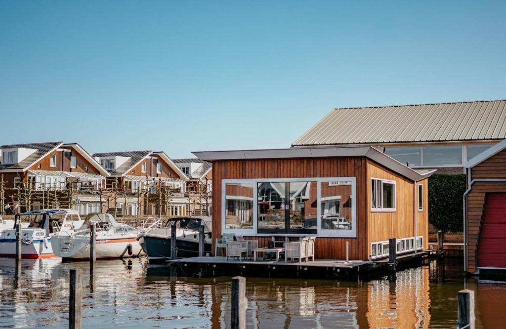 a house on a dock with boats in the water at Houseboat Uitgeest XL | 6 people in Uitgeest