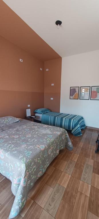 a bedroom with two beds and a wooden floor at Apê Estúdio Rodrigues 02 in Paranaíba
