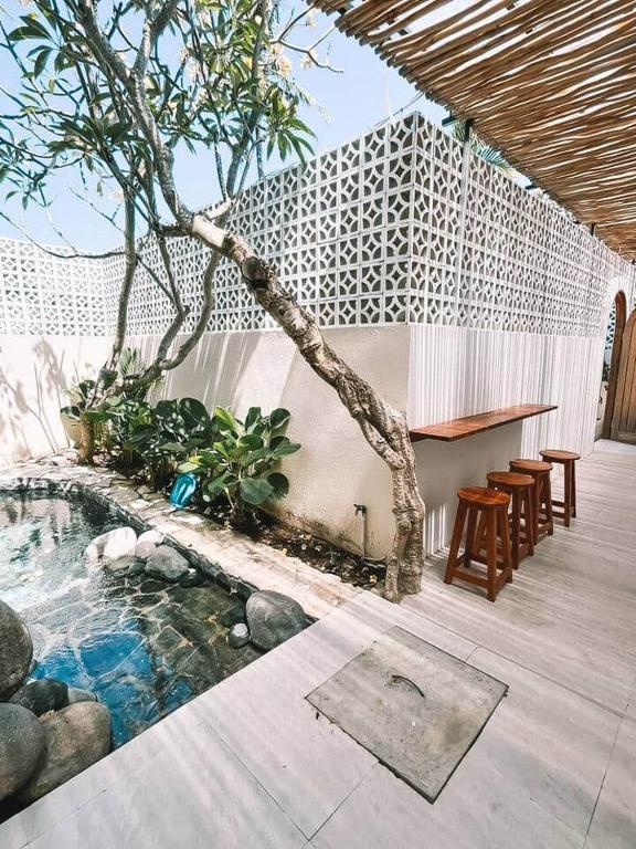 a patio with a pool with a table and chairs at Chic 2BR Villa w/Rock Plunge Pool in Denpasar