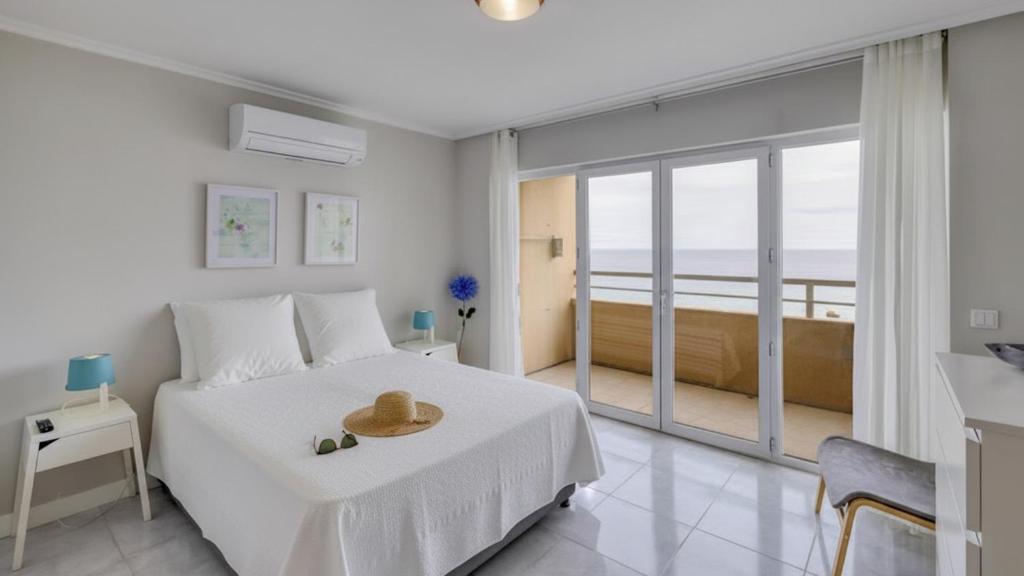 a white bedroom with a bed with a hat on it at Ocean View! 2-Bedroom Cosy Condo in Portimão
