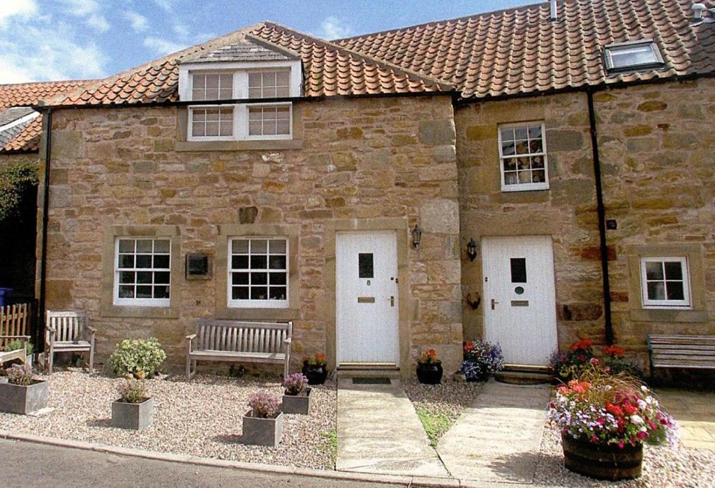een stenen huis met twee witte deuren en een bankje bij Kingsbarns Apartment in Kingsbarns