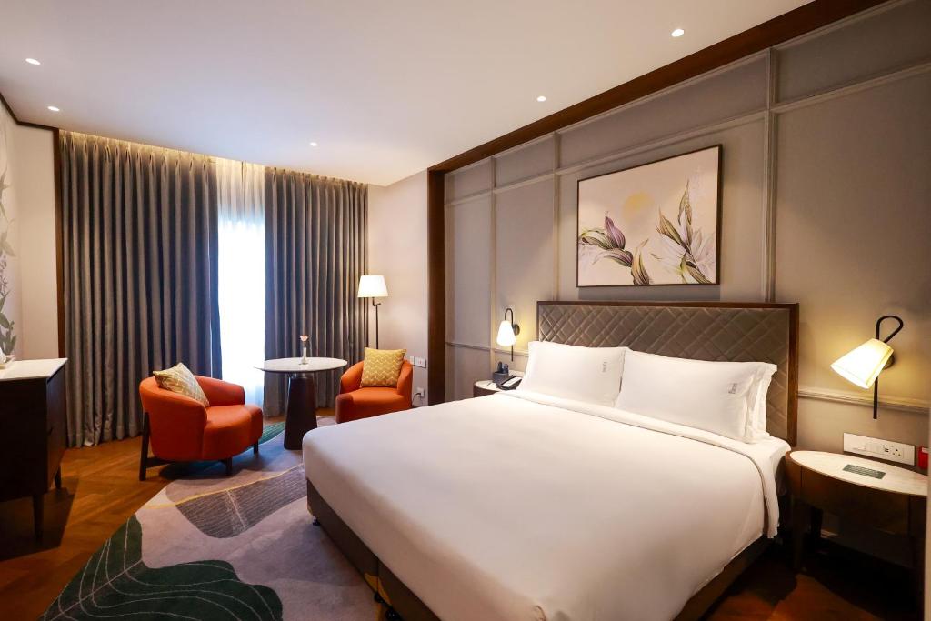 a hotel room with a large white bed and chairs at Holiday Inn New Delhi Mayur Vihar Noida by IHG in New Delhi