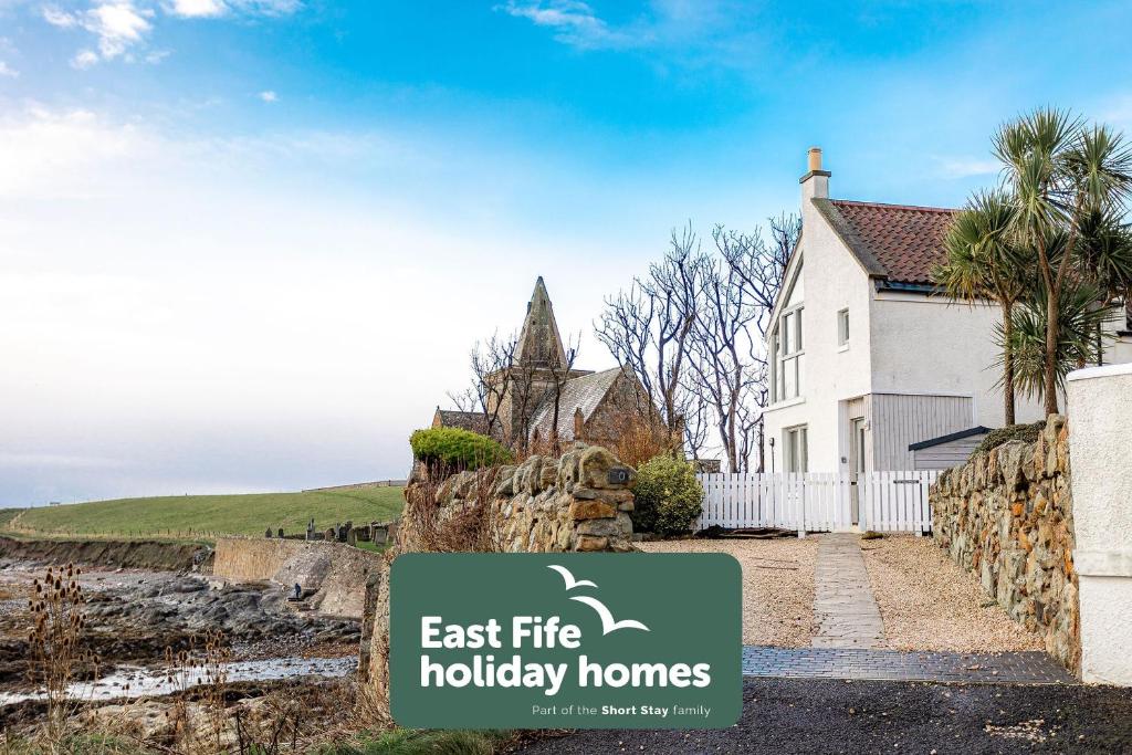 een huis met een bordje waarop staat: East Life Holiday Homes bij The Deck House - St Monans in Saint Monance