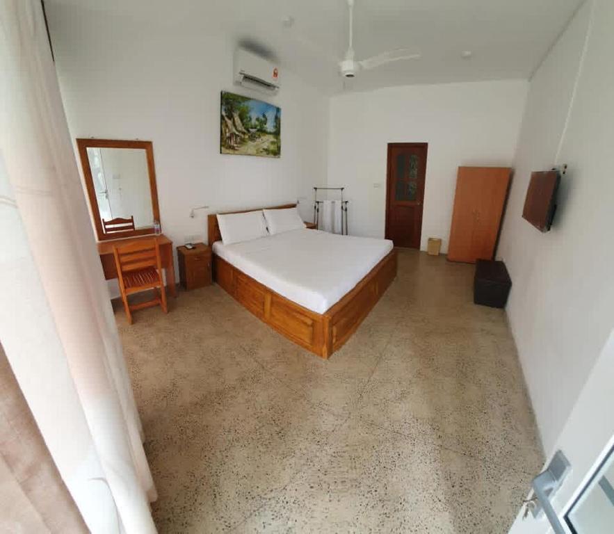 um quarto com uma cama, uma mesa e um espelho em Tabbowa Lake Resort em Nikawatawana