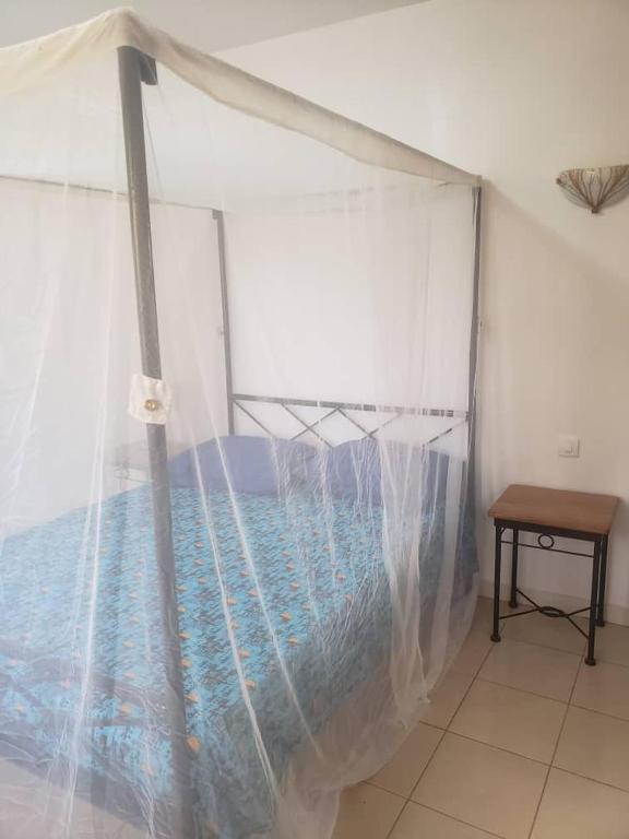 a bed with a canopy in a room with a table at Le Ganalé in Warang