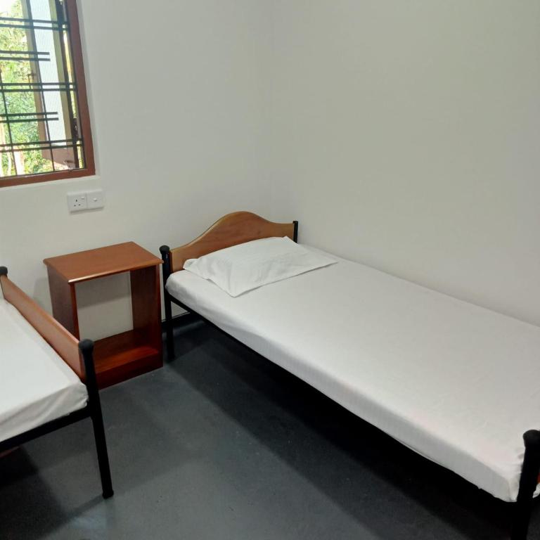 two beds in a room with a table and a bed at Cenesco Rest in Induruwa