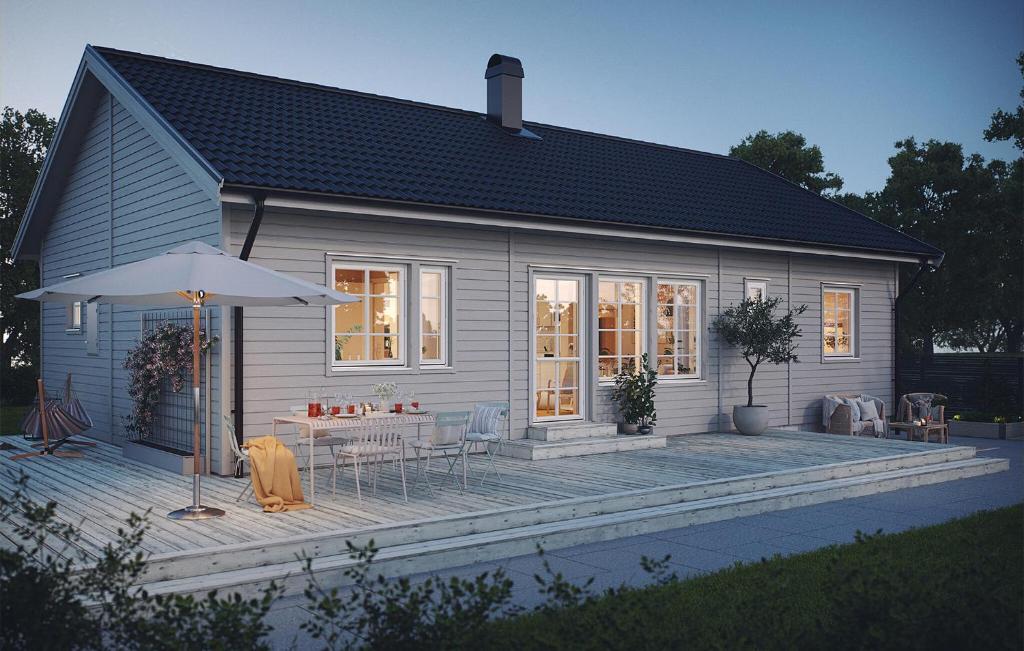a small white house with a table and an umbrella at 2 Bedroom Amazing Home In Färjestaden in Algutsrum