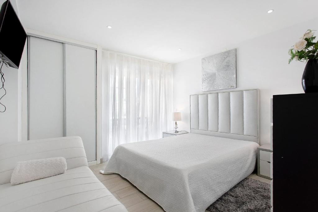 een witte slaapkamer met een wit bed en een bank bij Natalina T1 in Pederneira