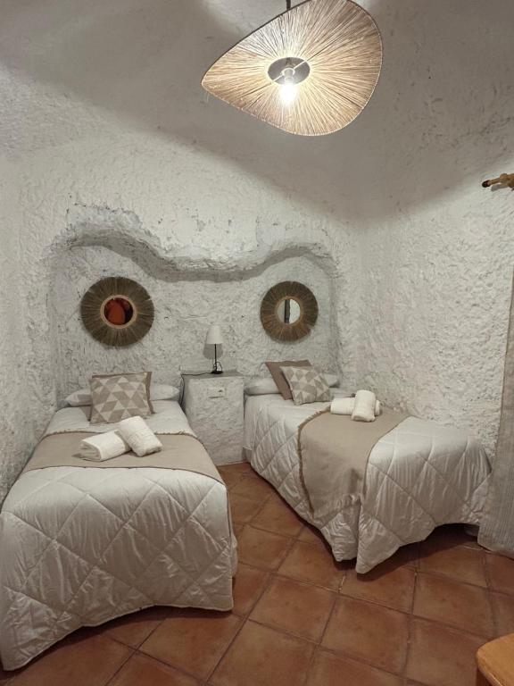 a bedroom with two beds and a chandelier at Bike Cueva - Desierto in Gorafe