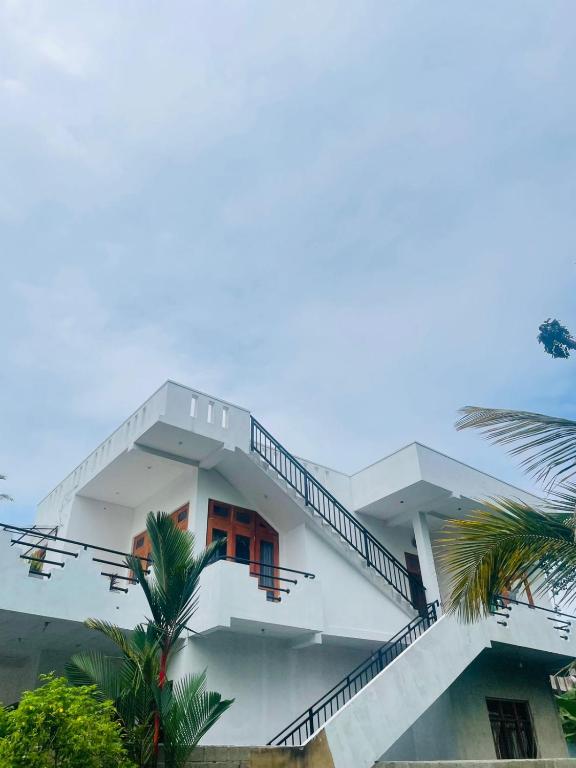 a white building with stairs and a palm tree at Villa Mangrove Serenity in Galle