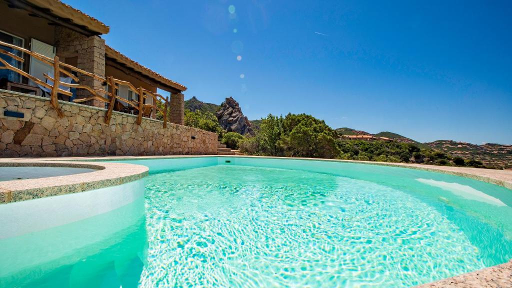 a swimming pool in front of a house at Futura anima sarda, villa sul tramonto con piscina privata in Costa Paradiso