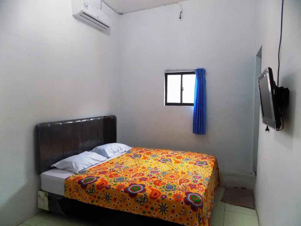 a small bedroom with a bed and a television at Amelia 2 Guest House Syariah in Medan